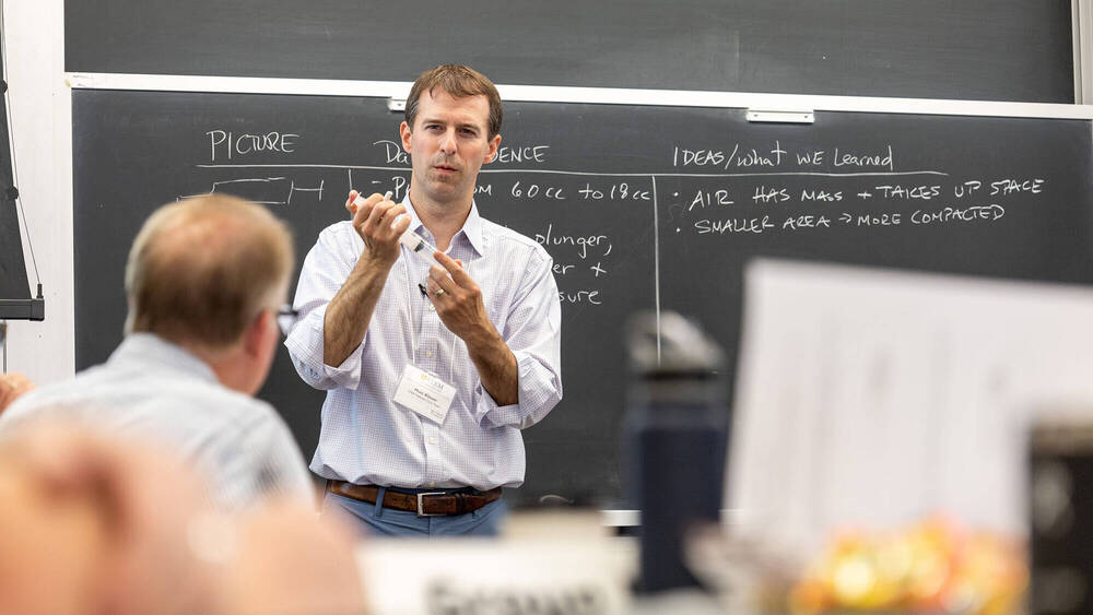 Educator in front of blackboard eliciting ideas about scientific gas laws